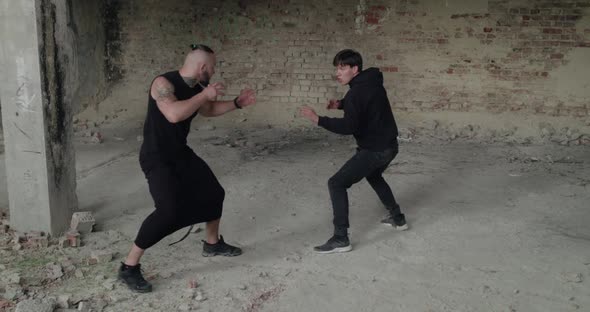 Skilful Fighting of Two Angry Men in Black Clothes in an Abandoned Building alt