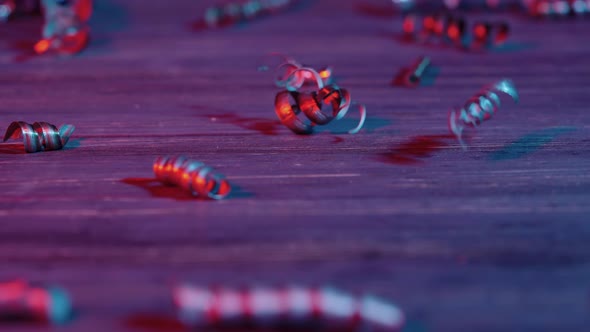 Shiny Metal Spiral Shavings Illuminated By Blue and Red Light Fall on Wooden Table alt