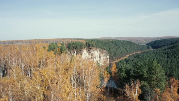 Aerial view; camera moving from behind autumn forest to river