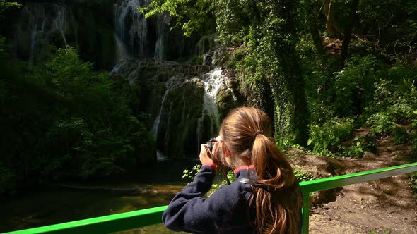 Girl is taking pictures of a beautiful waterfall alt