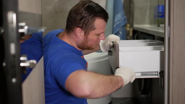 A Professional Furniture Maker In A Special Uniform Is Repairing A Curbstone. Screw The Screw alt