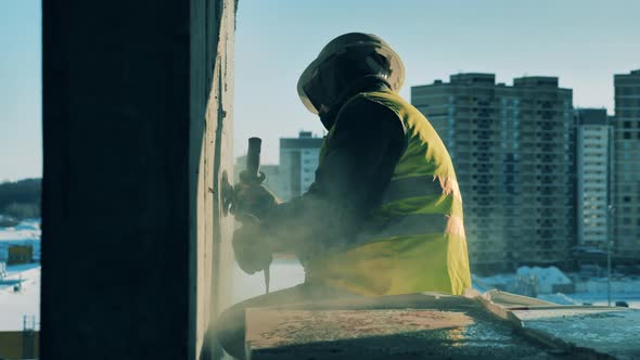 A Man Uses Sanding Machine While Working on a Building Site. alt