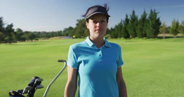 Portrait of female caucasian golf player crossing her arms while standing at golf course alt
