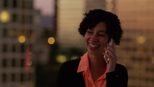 Woman talking on cell phone at night in city