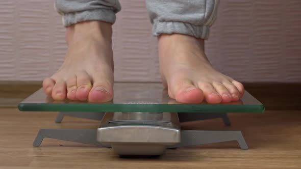 Women's Feet Stand on the Scales and Check Their Kilograms Front View alt