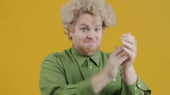 Portrait of Happy Young Man Applauding and Looking at Camera on Yellow Background alt