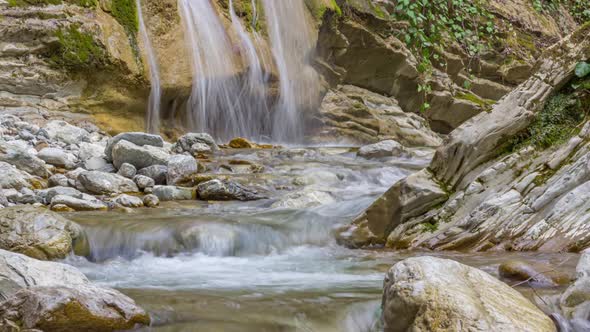 Zoom out view of a waterfall surrounded by stones