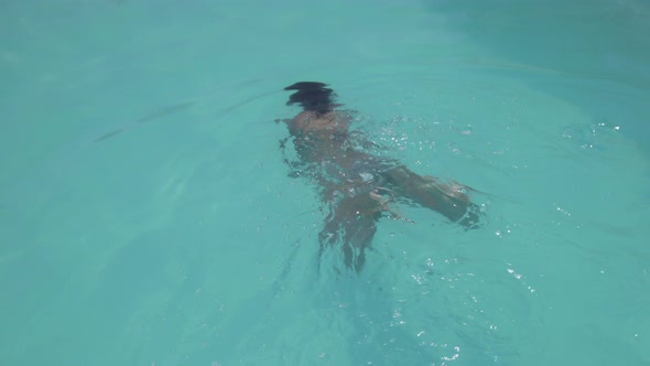Woman swimming and diving in outdoor swimming pool alt