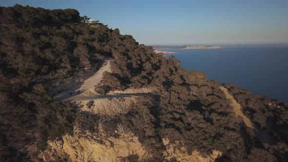 Extreme mountain biking trail by cliffs in Ibiza, Es Vedra, drone aerial alt