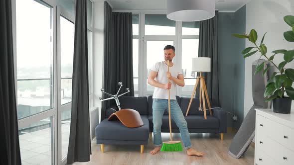 Man Cleaning the House and Having Fun Dancing and Singing with a Broom alt
