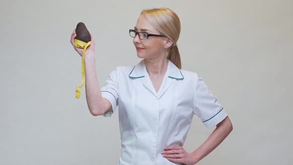 Nutritionist Doctor Healthy Lifestyle Concept - Holding Organic Avocado Fruit and Measuring Tape alt