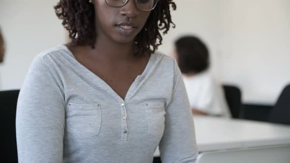 Thoughtful African American Woman in Eyeglasses Typing on Laptop alt