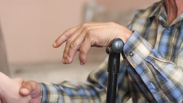 a child helps a pensioner with a walking stick to get up after an illness. a helping hand from a gra alt