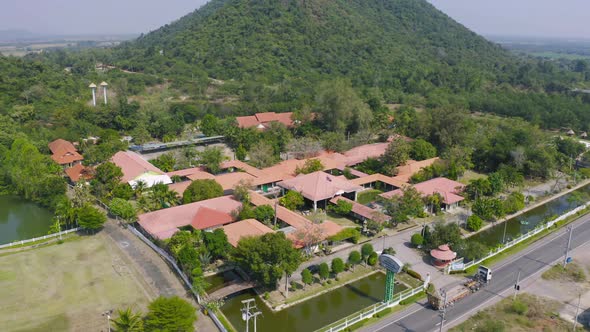 Aerial view of Thai village, hotel resort on green mountain hills with forest trees, Ratchaburi,