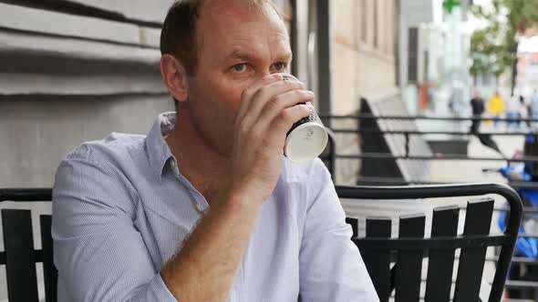Portrait Caucasian Adult Man with Gray Eyes in a Blue Shirt Drinking Coffee Outdoors in a Cafe with