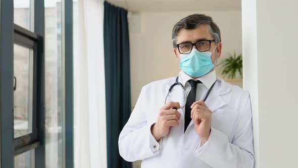 Portrait of a Senior Doctor in White Suit and Protective Mask alt