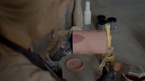 Young Woman Decorator Paints a Jar with Paints