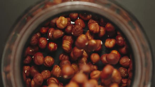 TOP VIEW: Peeled Nuts Falling Into A Glass Jar - Slow Motion alt