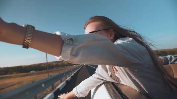 Free Woman Rides in a Car Catches the Wind with Her Hand From the Car alt