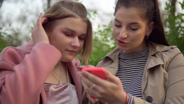 Women Friends Looking at Phone Screen Walking at Park Friendship Concept