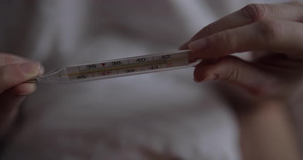 Woman in Bed Hold Thermometer in Hand alt