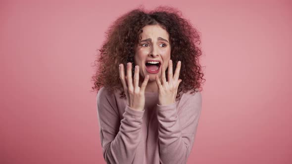 Close Up of Young Scared Curly Girl Shouting Isolated Over Pink Background.  alt