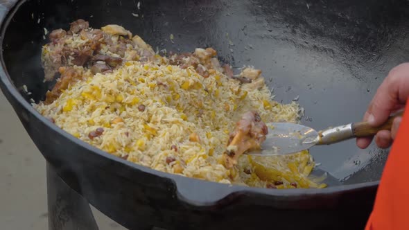 Slow Motion: Chef Cooking Pilaf in Huge Cauldron at Summer Outdoor Food Market