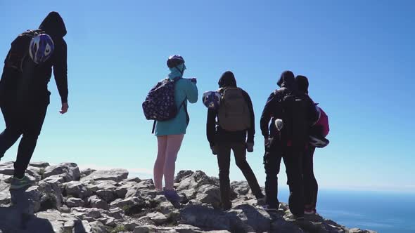 Tourists Approach on Top of the Mountain and Looking at the Sea Below, Back View