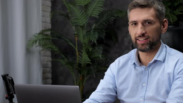 Close Up Man Stock Trader Broker Work for Laptop Turns Head to Camera with Smile alt