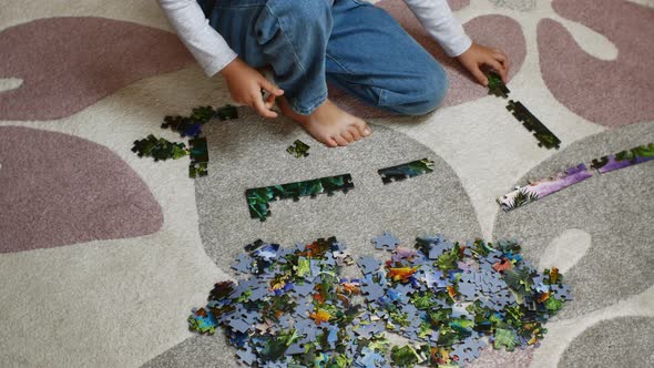 A Preschool Girl Sits on a Carpet and Collects Colorful Puzzles