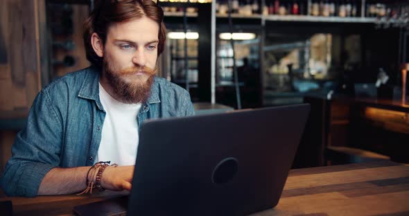 Hipster Male Browsing Laptop in Cafe