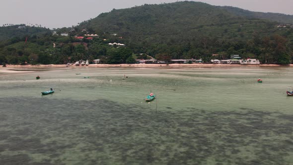 Flying above Nathon turquoise sea water beach in Koh Samui island, wooden boats alt