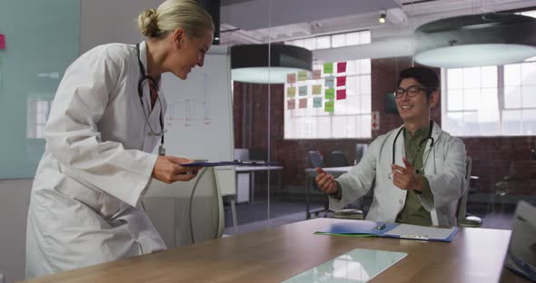 Diverse male and female doctors on meeting greetings shaking hands in meeting room alt