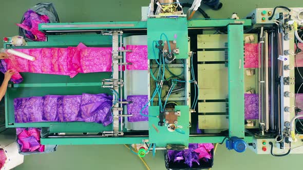 Female Worker Packing Colourful Plastic Bags From a Production Line Into a Box alt