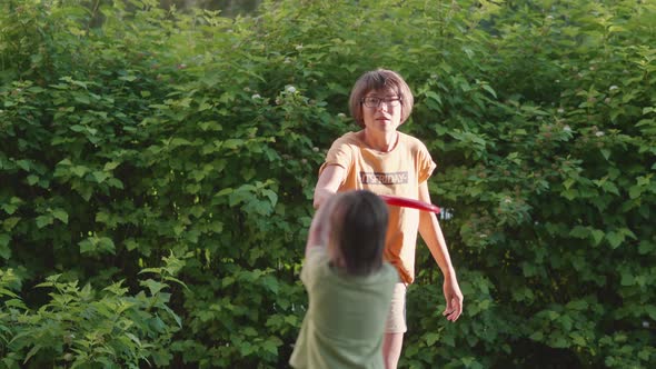 Mother and Son Play Frisbee on Grass Lawn alt