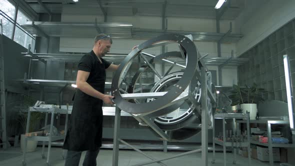 Design engineer assembles a metal frame in an assembly shop in a factory