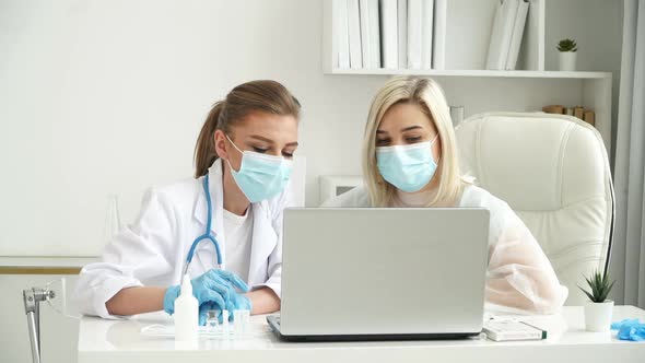 Team of Female Doctors in Protective Masks Discuss Patients Diagnosis at Laptop in Clinic