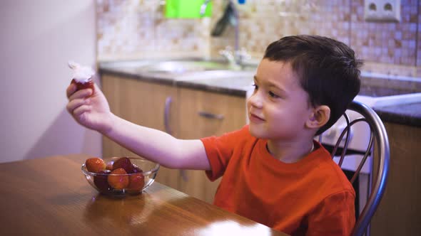 A Boy Eats Strawberries with Cream with Which His Mother Wateres Strawberries