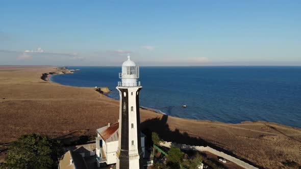 Aerial View of an Unknown Lighthouse with Black and White Edges on the Peninsula's Promontory alt