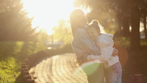 Mother and Daughter Hugging While Walking in the Park