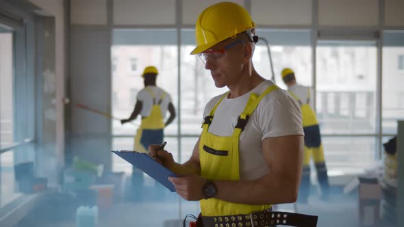 Senior Foreman Checking and Inspecting with Clipboard at Construction Site alt