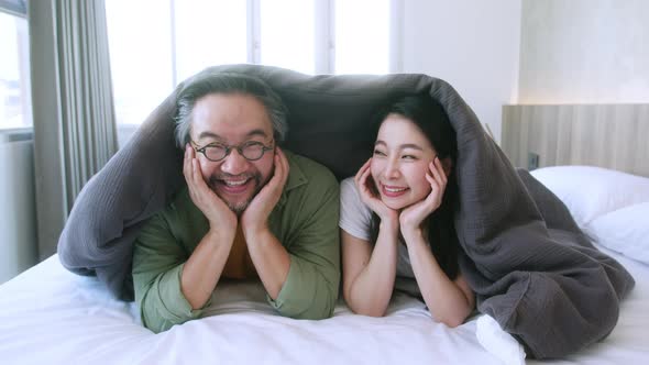 t Asian marry couple family mom dad laying laugh smile on white soft bed