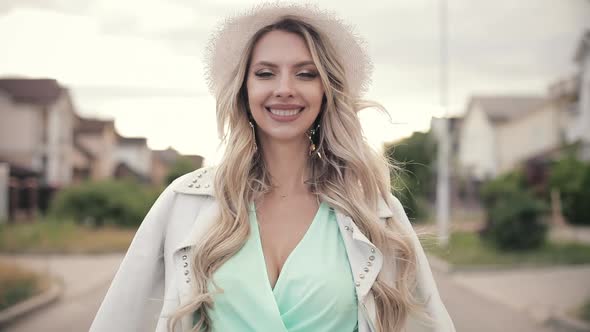 Portrait of Beautiful Woman in Long Mint Dress, White Hat and White Jacket Smiles