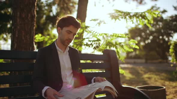 Slow Motion of Successful Corporate Man Businessman Sitting on Bench in Park and Readig Newspaper