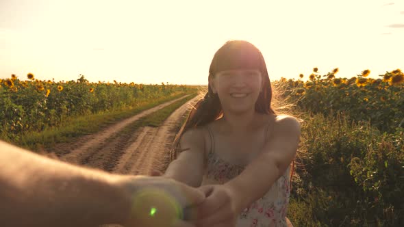 Girl and Guy Rkuka in Hand, in Evening Walk Along Field with Sunflowers at Sunset, Holding Hands. A alt