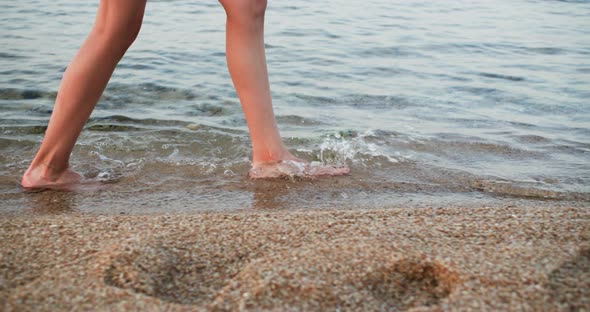 Barefooted Woman is Walking in Water on the Sea Sand Beach Legs Closeup