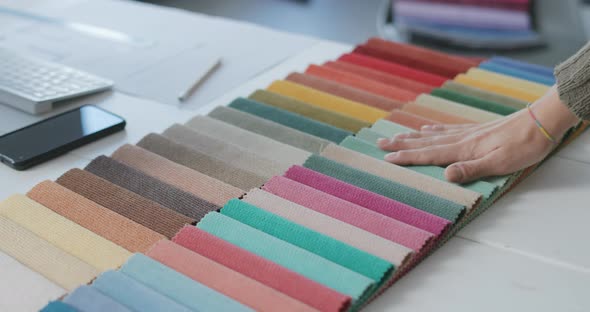 Woman touching colorful fabric swatches on a desk