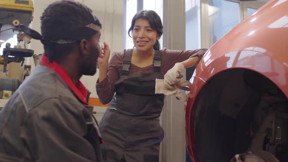 Female Mechanic Talking with Male Colleague in Garage alt
