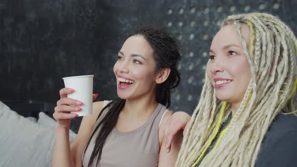 Smiling Charismatic Female Talking to Her Friend and Pointing Finger to the Window alt