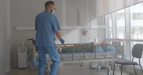 Medical Team Opening Curtain and Resuscitate Sick Aged Patient Lying in Bed at Hospital alt